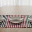 Un ensemble de quatre sets de table en coton vert à carreaux, résistants aux taches : rond, ovale, rectangulaire et carré.