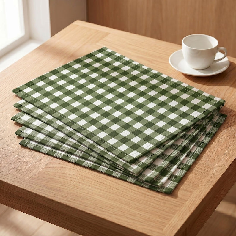 Un ensemble de quatre sets de table en coton vert à carreaux, résistants aux taches : rond, ovale, rectangulaire et carré.